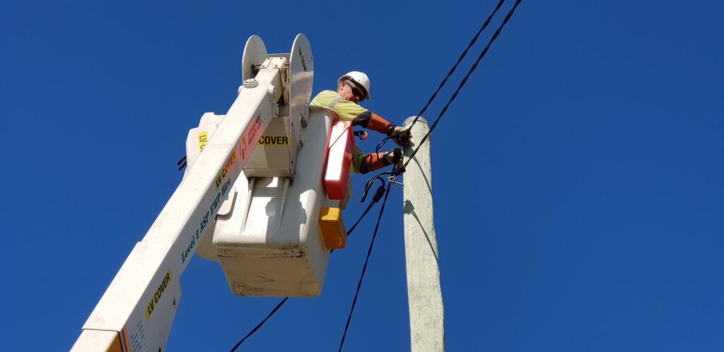 ASP Level 2 electrician working from an elevated platform on overhead power lines